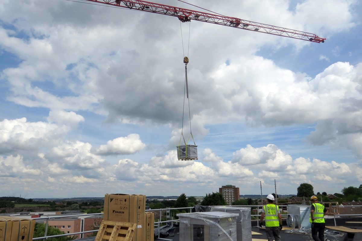 Riggers supervising a rooftop crane lift